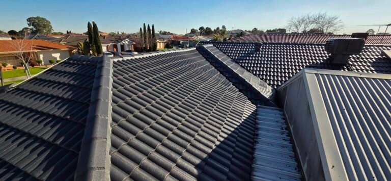 After: freshly restored charcoal tiled roof with ridge capping under a blue sky in Sydenham