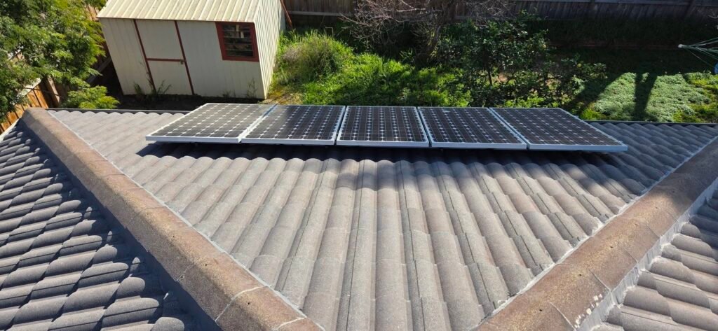 Before: weathered grey tiled roof with five solar panels in Sydenham