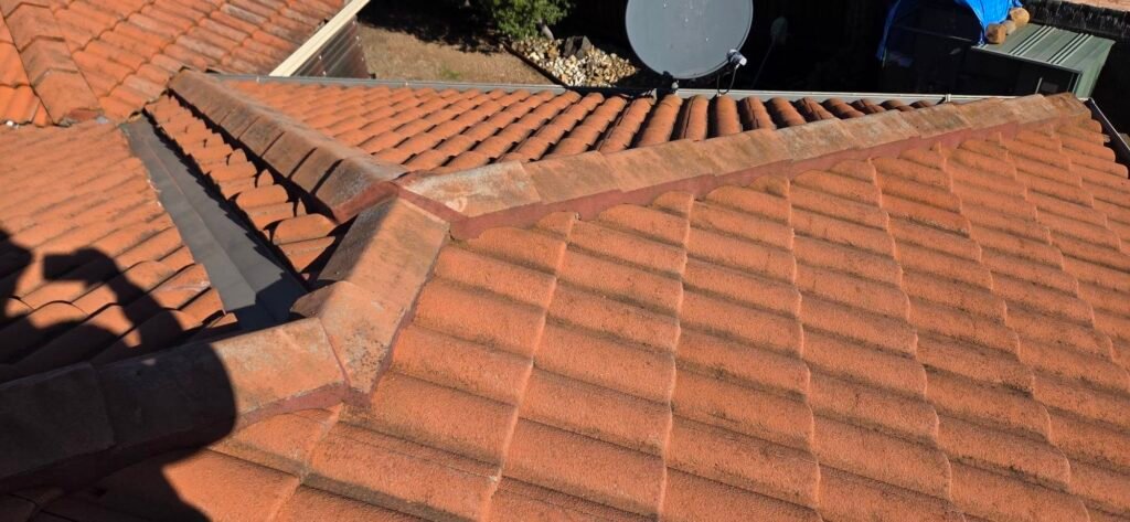 Before: hip and ridge junction with worn pointing on a tiled roof in Hillside