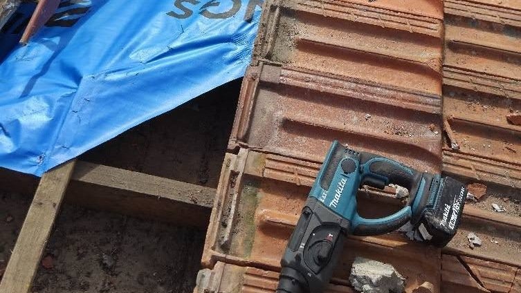 Blue sarking and a rotary hammer beside terracotta roof tiles during a roof repair in Essendon