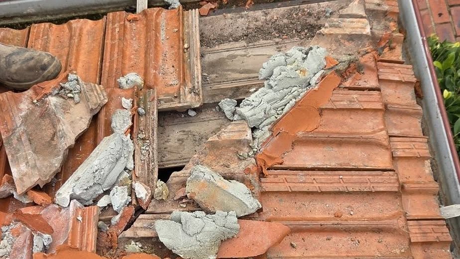 Crumbling mortar and broken terracotta tiles at a leaking roof section in Essendon