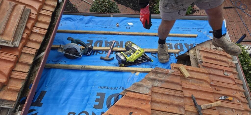 New blue sarking and battens with tools laid out on a terracotta tiled roof during repairs in Essendon